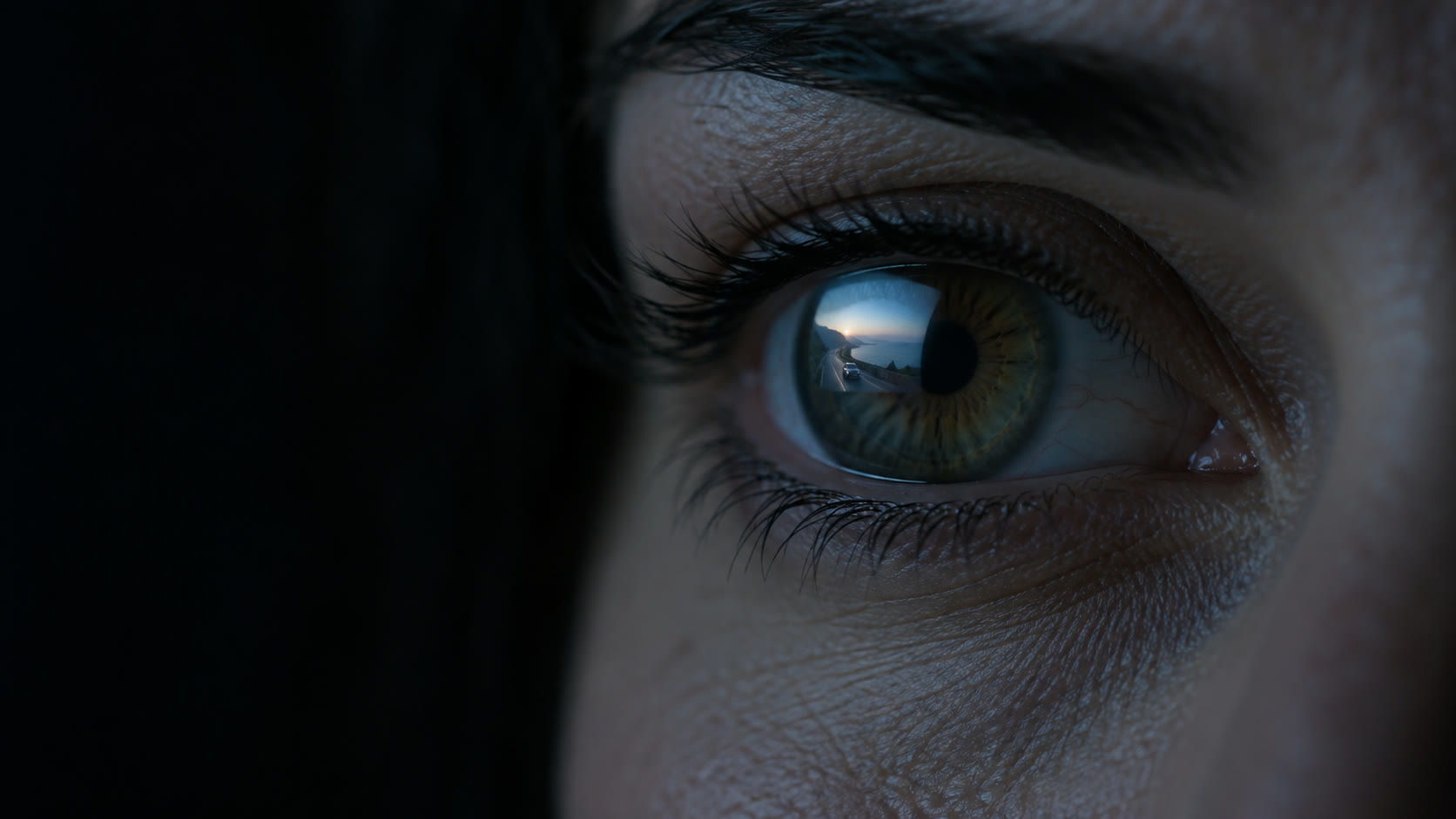 Close-up of an eye reflecting a TV screen