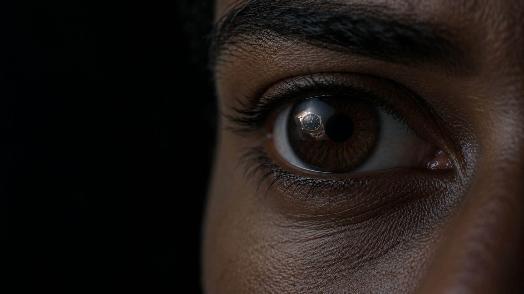 Close-up of an eye reflecting a wristwatch